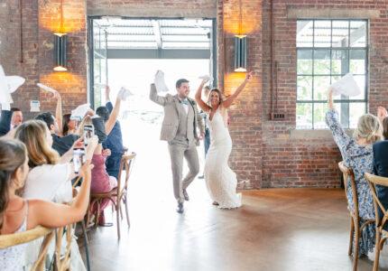 happy couple making at wedding entrance at Bishop Station