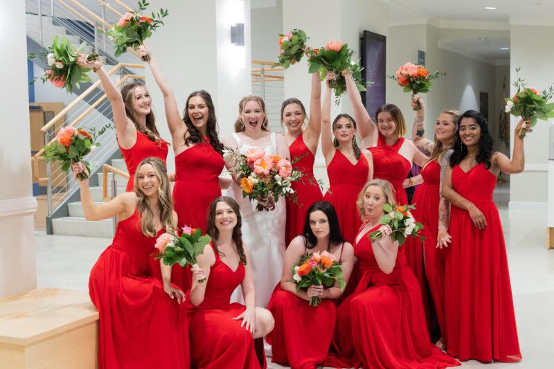 bridesmaids in bright red dresses holding vibrant flowers