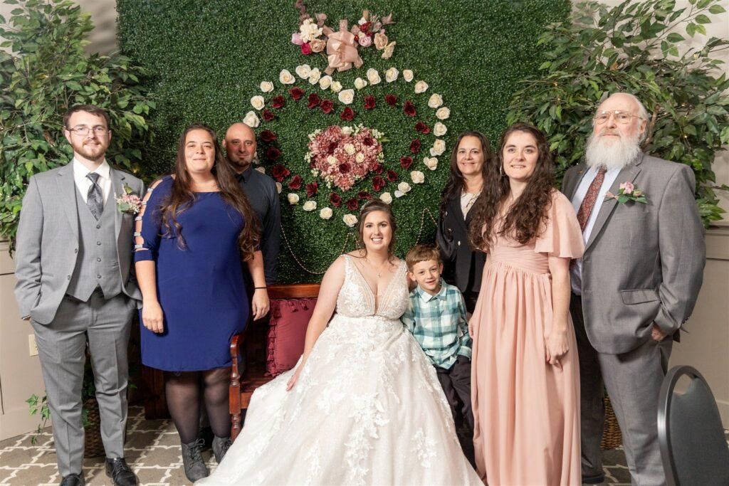 Bride at a wedding and her family posing for a photo